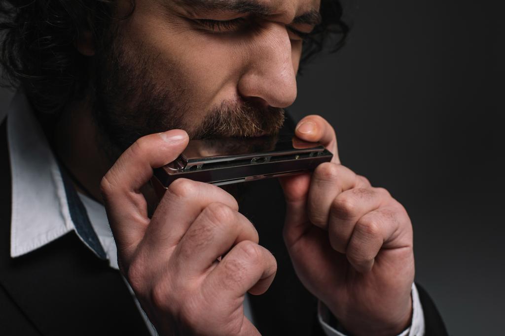 Hohner shop -Hohner shop stock photo close up portrait of expressive musician playing harmonica on black